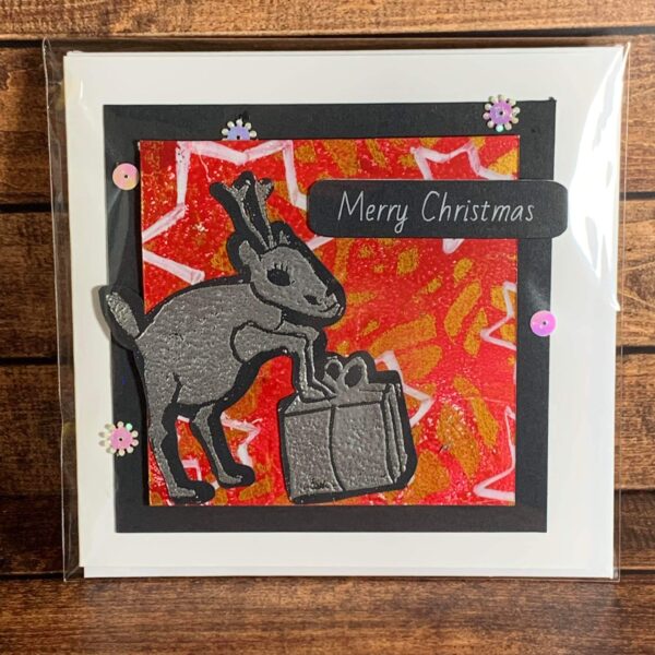 Cellophane wrapped Silver Reindeer with Present on Starry Background