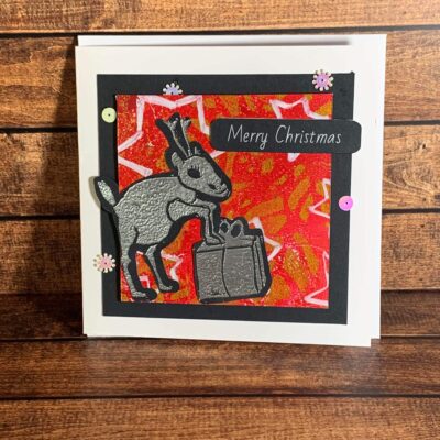 Cheerful Silver Reindeer with Present on Starry Background Print